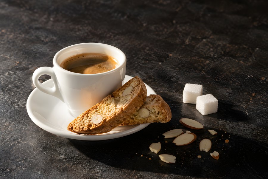 Espresso Cup with Almond Biscotti, Sugar Cubes and Sliced Almonds on a Dark Stone Table