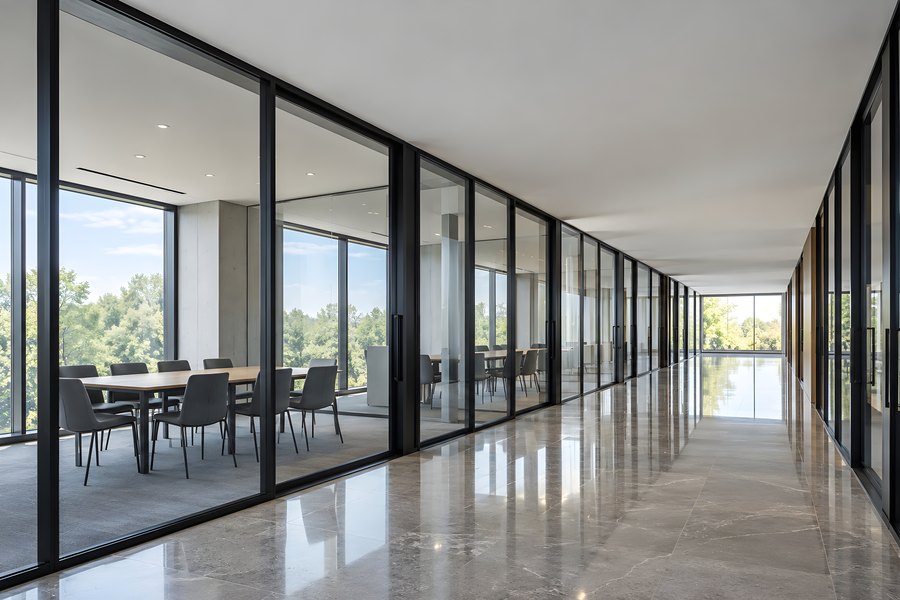 Empty office corridor with black-framed glass partitions and reflective marble floor