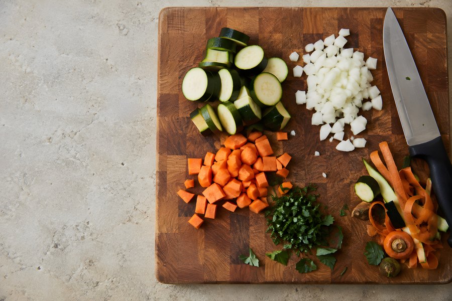 Chopped Vegetables and Knife on a Wooden Chopping Board in a Kitchen, Overhead View