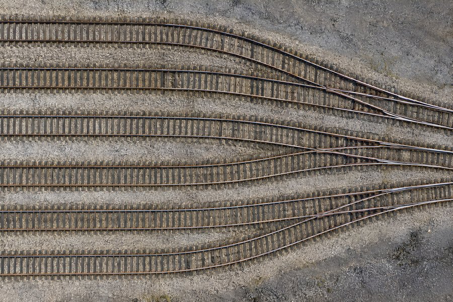 Aerial view of railway tracks converging through a switch junction on gravel ballast, no train in sight
