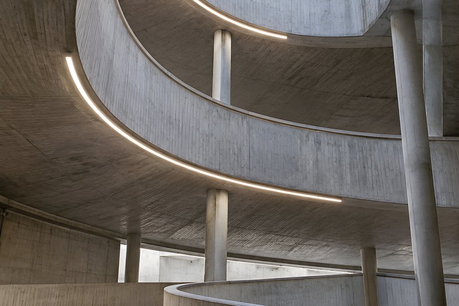 Empty spiral parking garage ramp with curved concrete levels and LED strip lighting, no cars or people