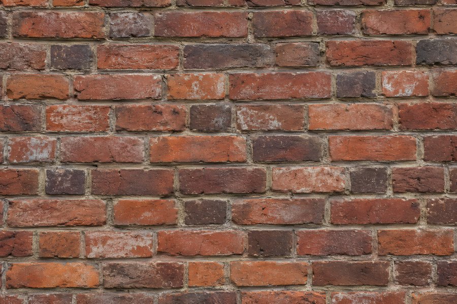 Weathered red brick wall texture with running bond pattern and recessed mortar joints