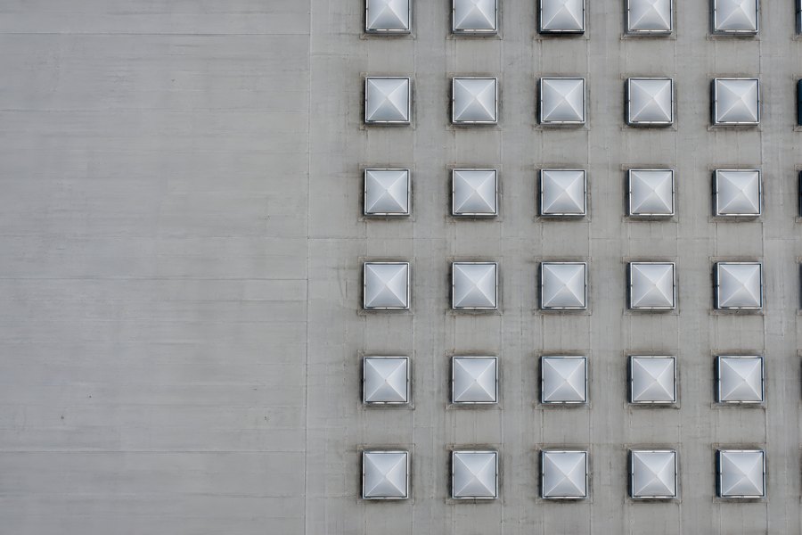 Aerial top-down view of a flat rooftop with a grid of pyramid skylights and bare concrete surface